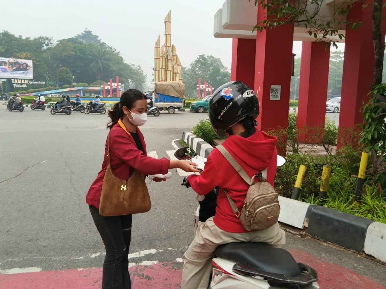 Mahasiswa membagikan masker kepada pengguna jalan di Bundaran Digulis, Pontianak, saat kondisi kabut asap akibat karhutla, Sabtu (26/9/2026).