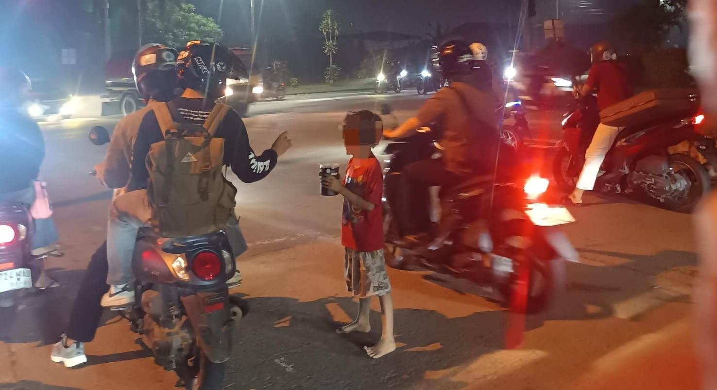 Anak-anak berada di persimpangan jalan dan meminta uang kepada pengendara, dengan suasana lalu lintas di Jalan Adisucipto, Simpang Tol 2, Kabupaten Kubu Raya.